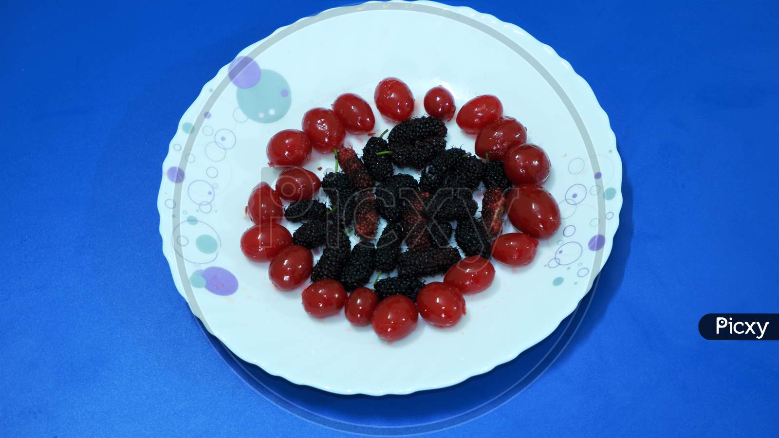 Red berries and mulberry on white plate