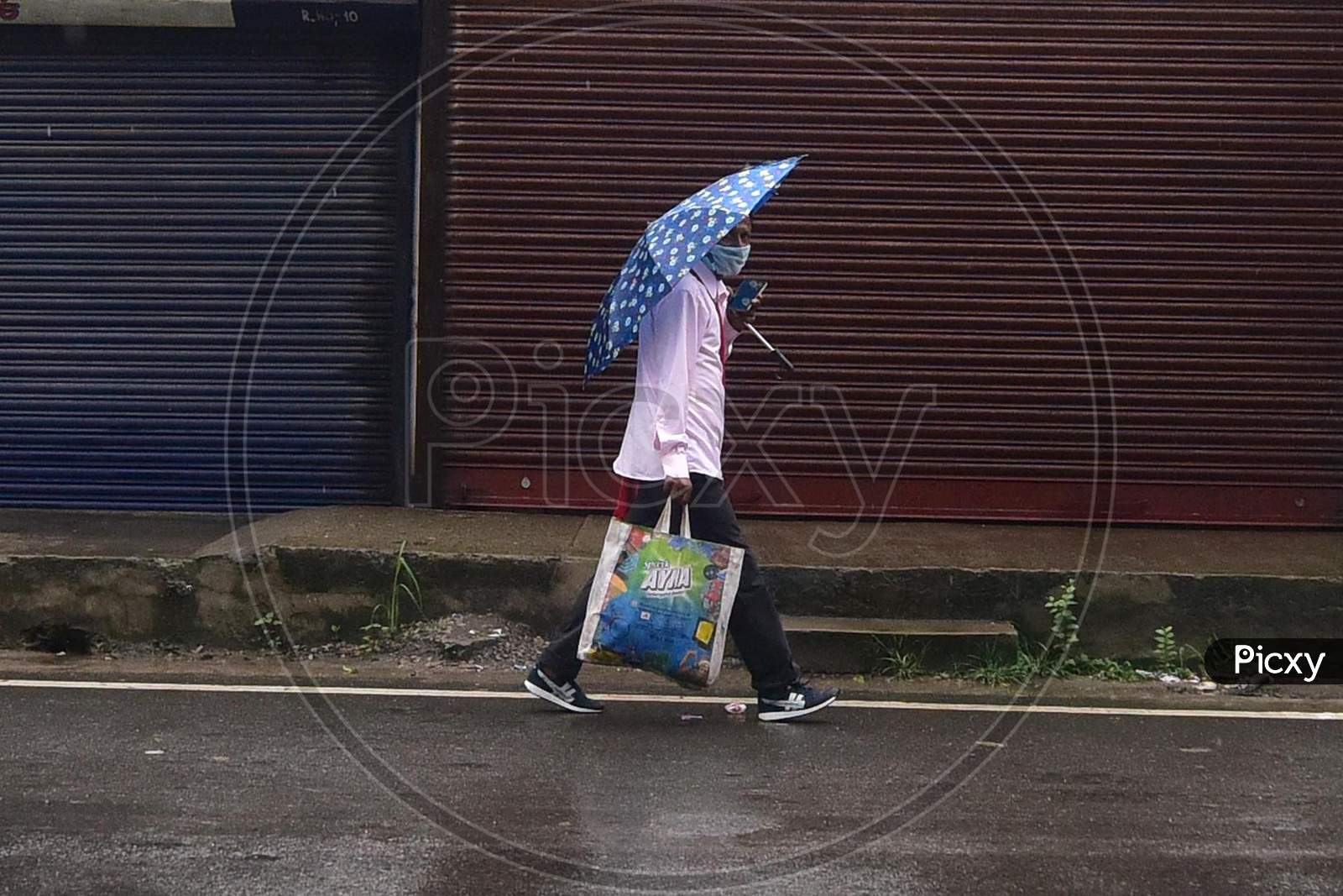 A man Walks near Closed Markets During Rains In Nagaon District Of Assam On  Saturday, June 27, 2020. Authority Announced The Imposition Of A Weekend Lockdown In All Urban Areas Of The State