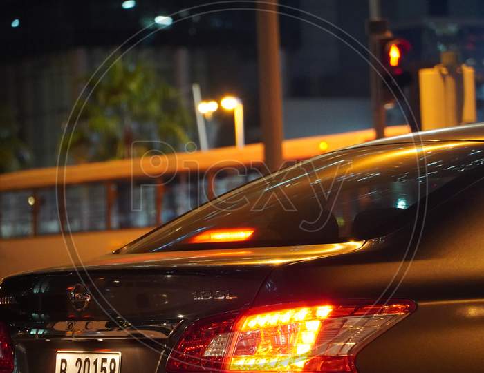 Dubai Uae - November 2019: Rear View Of Nissan Sedan Car Close Up Picture Taken At Night Time Parked. Close Up Shot Of Back Side Of Dark Black Car With View Of Rear Lights, Tail Lights.