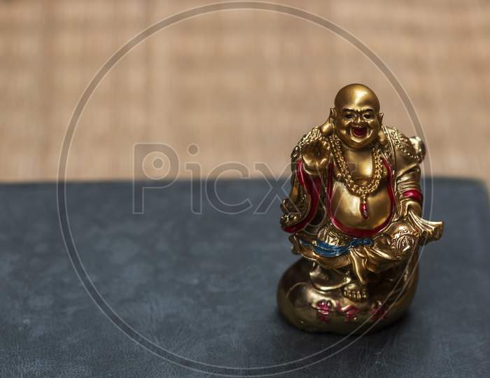A laughing Buddha kept in a book with jute texture in the background