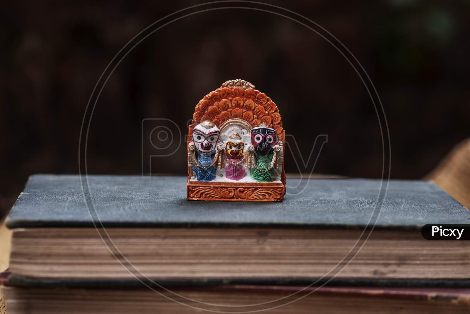An idol of Lord Jaganath kept in a old book with dark wall in the background