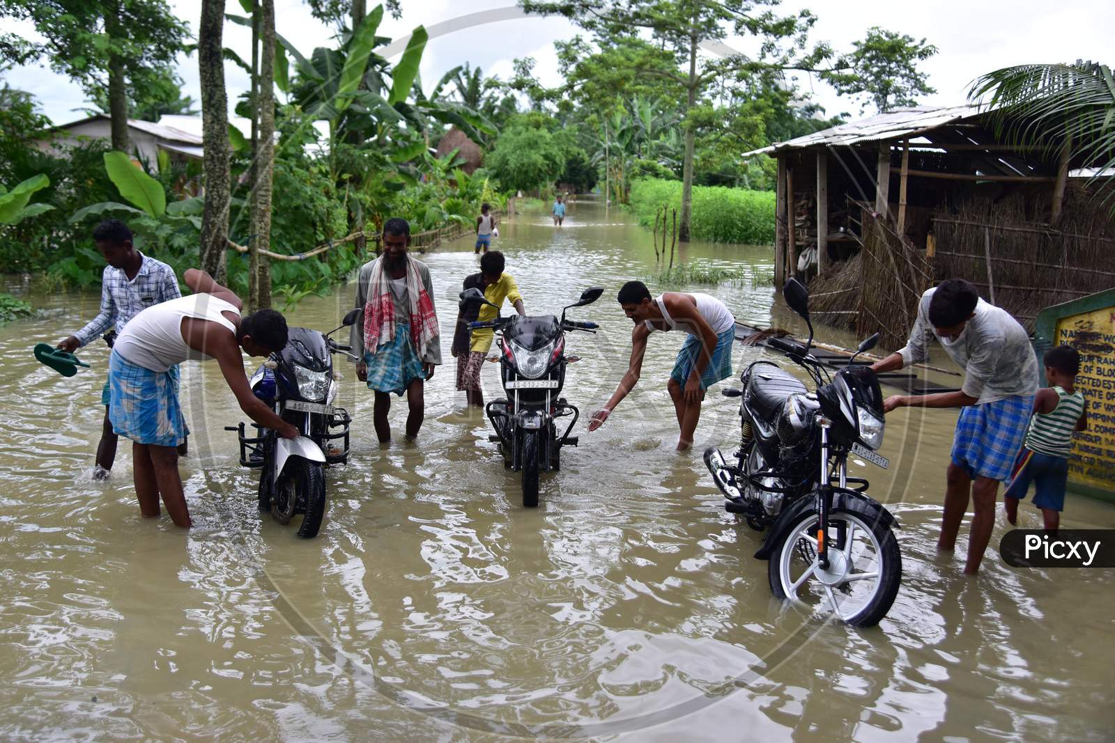 People Clean Their Bike In Floodwaters Following Heavy Rainfall At Bhurbandha Village In Nagaon District Of Assam On June 27,2020.