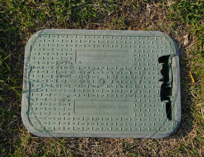 Dubai Uae December 2019 An Old Broken Plastic Box For Irrigation Control Valve With Background Of Dry Green, Brown Grass. Green Valve With Automatic Watering System Installed Under Outdoor Lawn.