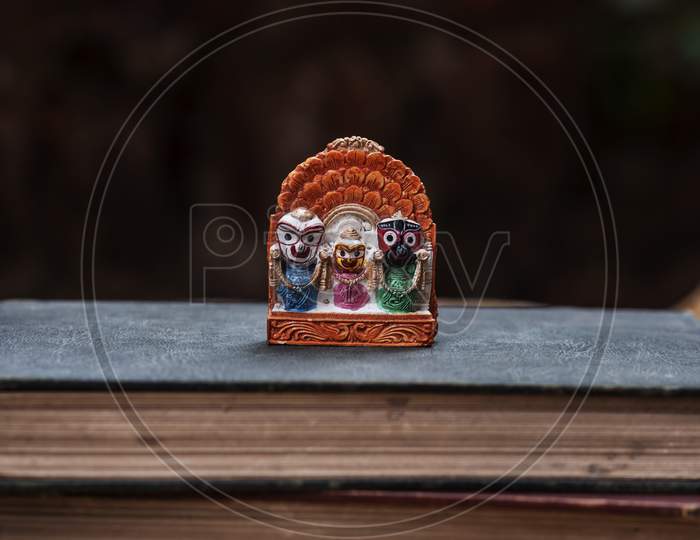 An idol of Lord Jaganath kept in a old book with dark wall in the background