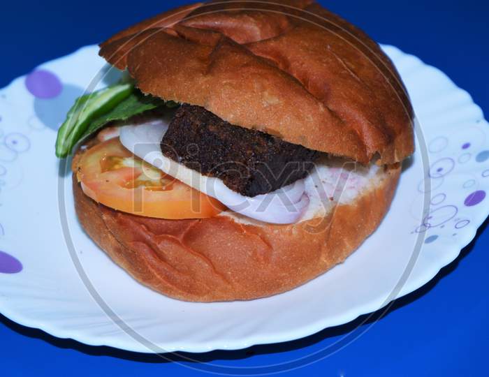 stuffed big burger on white plate and blue background