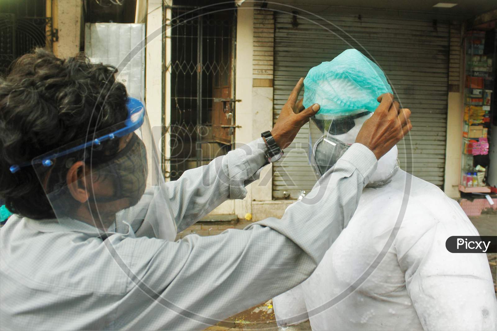 A shopkeeper adjusts the cap of a PPE kit makeshift mannequin, in Mumbai, India on June 20, 2020.
