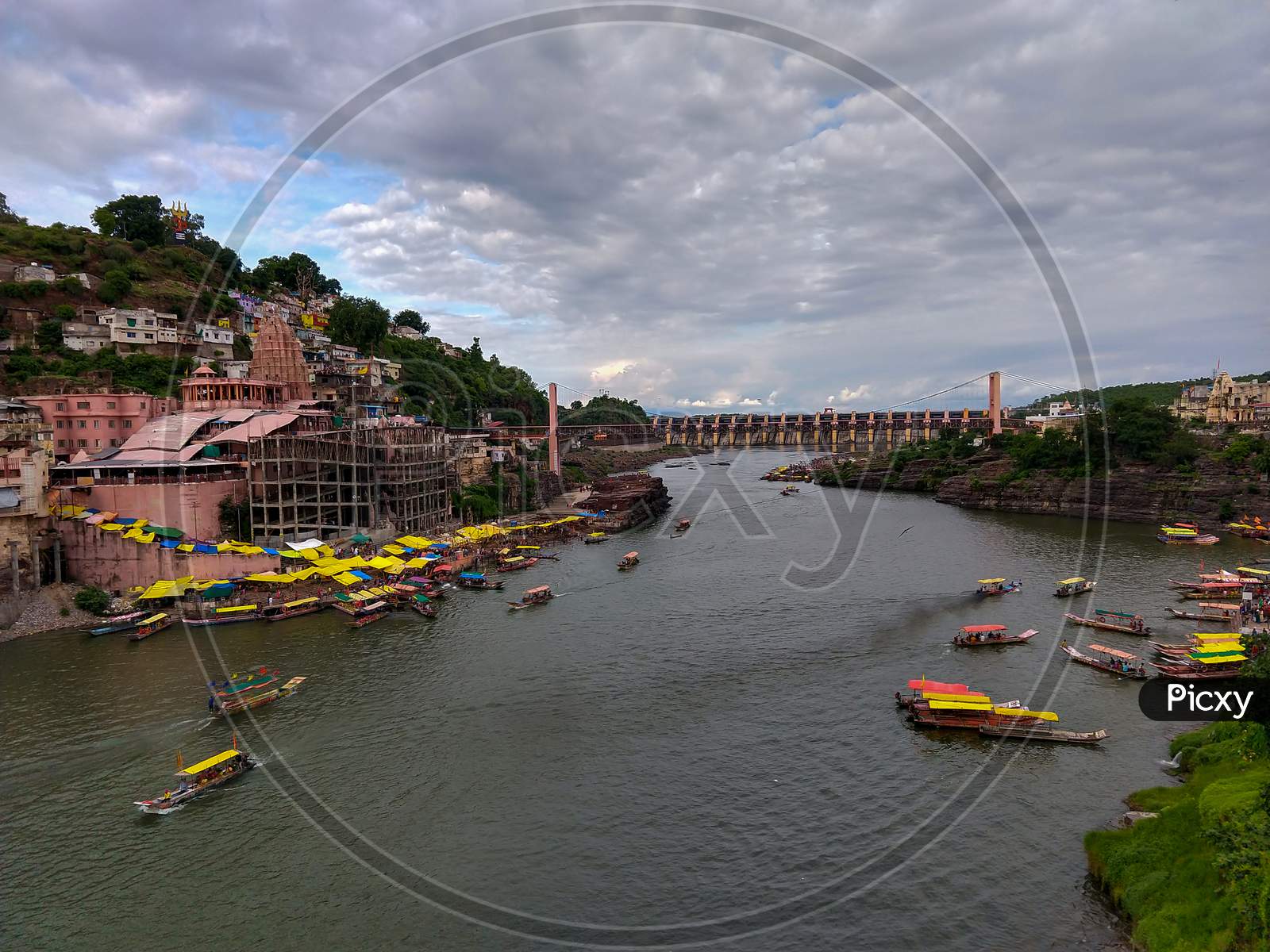 Famous Omkareshwar Jyotirling Temple, Omkareshwar Dam And Holy Narmada River All Are In One Frame. Colorful Boats Are Floating In The River.