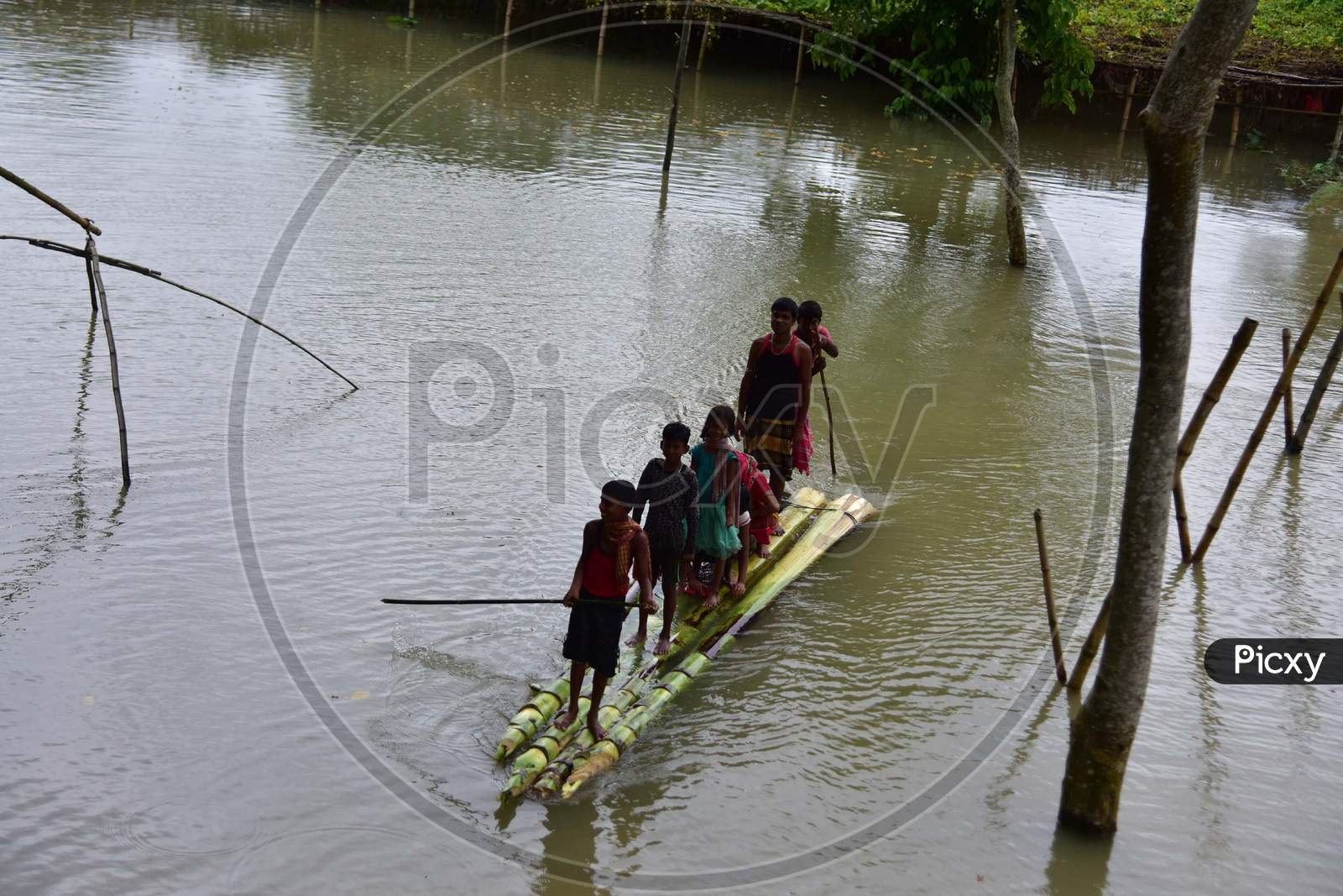 People wade through Floodwaters On A Makeshift Banana Raft Following Heavy Rainfall At Bhurbandha Village In Nagaon District Of Assam On June 27, 2020.