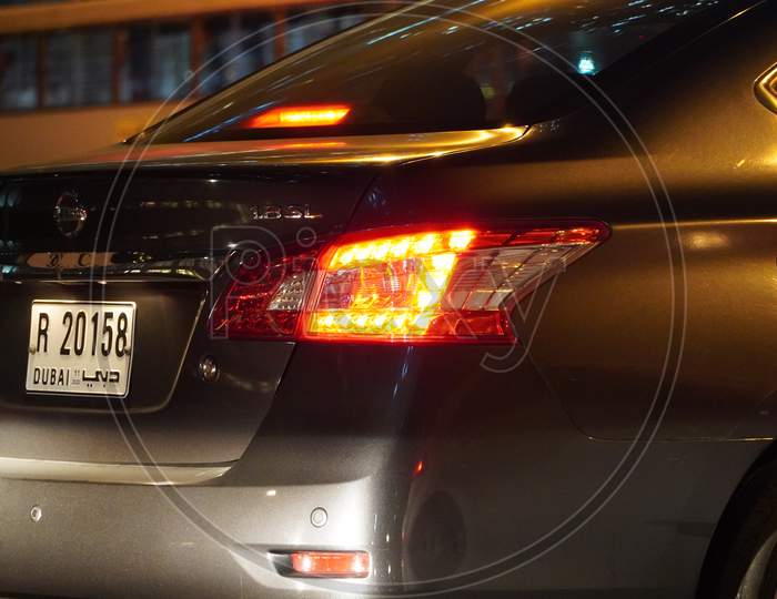 Dubai Uae - November 2019: Rear View Of Nissan Sedan Car Close Up Picture Taken At Night Time Parked. Close Up Shot Of Back Side Of Dark Black Car With View Of Rear Lights, Tail Lights.