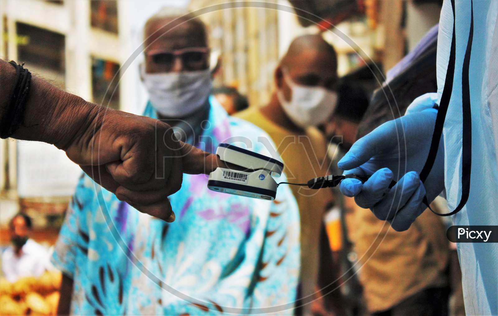 People watch as a healthcare worker measures the pulse of a resident at Dharavi, as a preventative measure against the spread of coronavirus disease, in Mumbai, India on June 21, 2020.