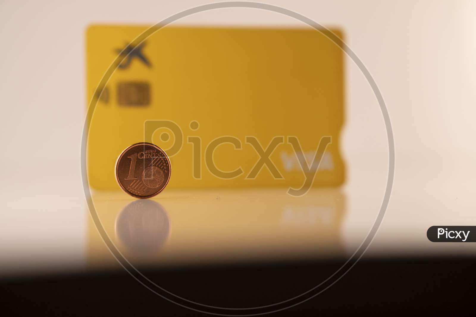 one euro coin and debit visa card against a white background.