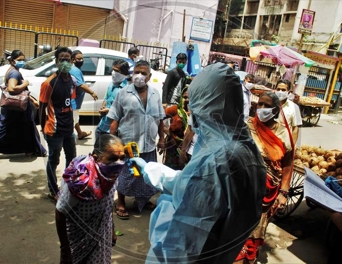 A health care worker wearing personal protective equipment (PPE) checks the temperature of a resident at Dharavi, one of Asia's largest slums, as a preventative measure against the spread of coronavirus disease, in Mumbai, India on June 21, 2020.