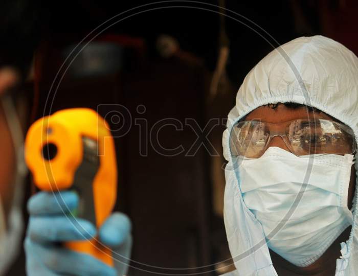 A health care worker checks the temperature of a resident at Dharavi, one of Asia's largest slums, as a preventative measure against the spread of coronavirus disease, in Mumbai, India on June 21, 2020.