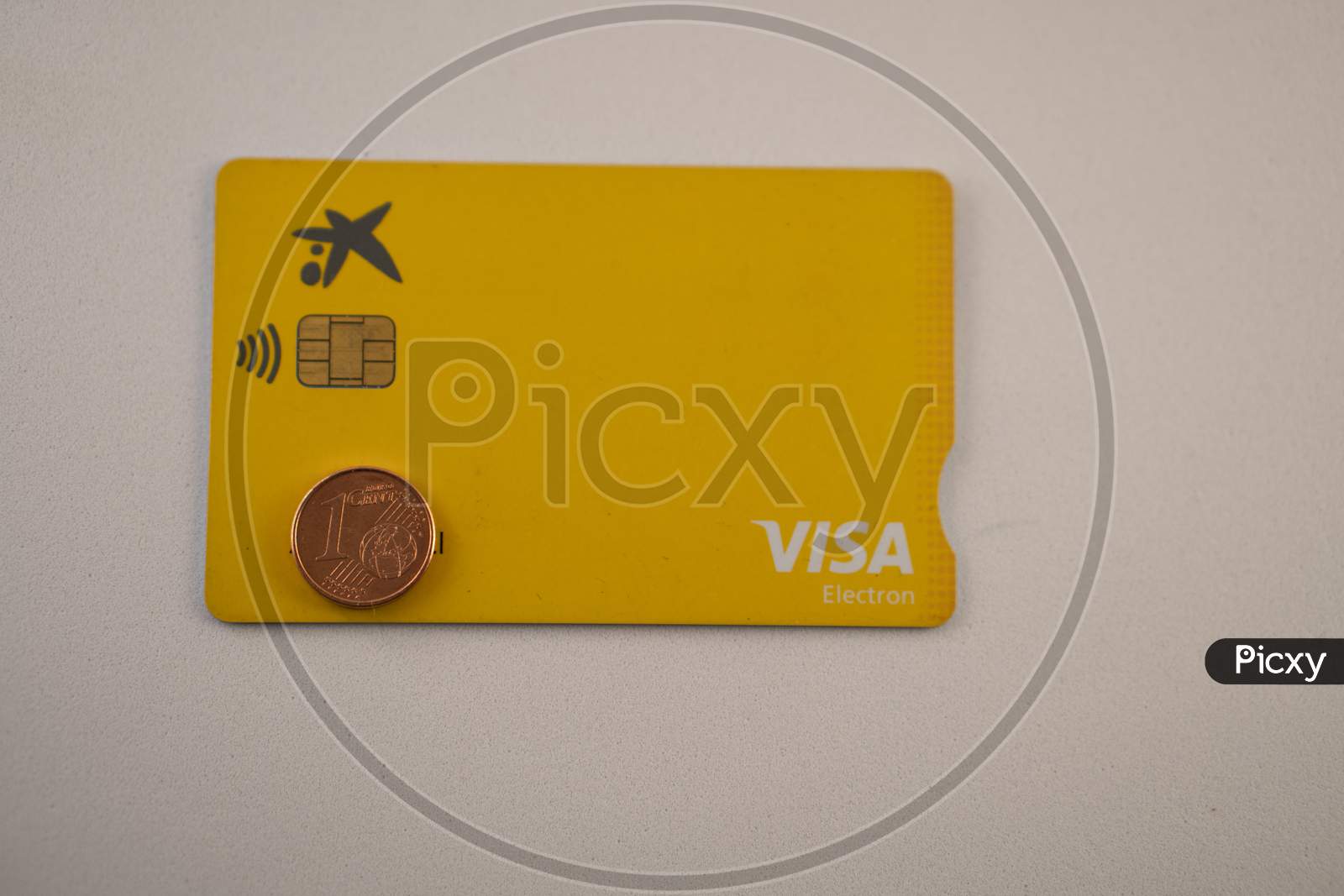 one euro coin and debit visa card against a white background.