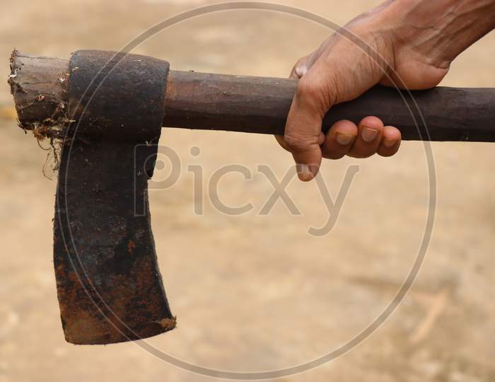 Very Old And Rusty Axe With Wooden Handle Held In Hand