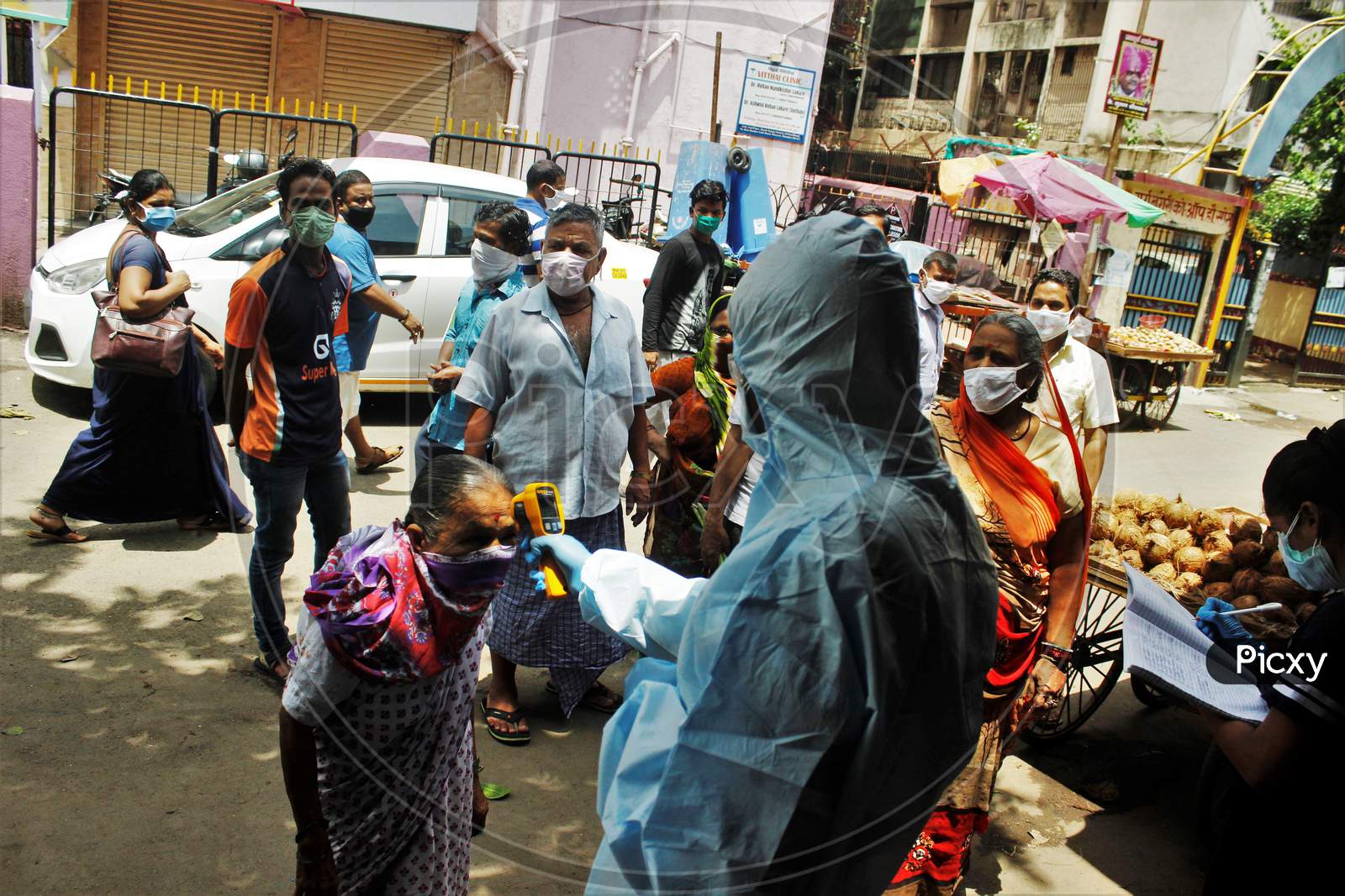 A health care worker wearing personal protective equipment (PPE) checks the temperature of a resident at Dharavi, one of Asia's largest slums, as a preventative measure against the spread of coronavirus disease, in Mumbai, India on June 21, 2020.