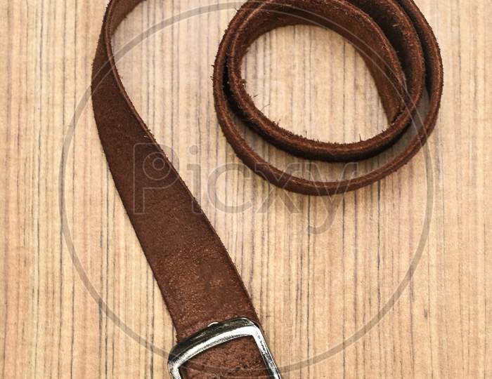 Brown Leather Belt on Dark Wooden Desk