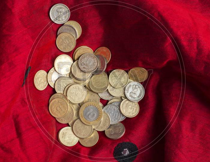 Indian five and ten rupee coins are kept in a red cloth