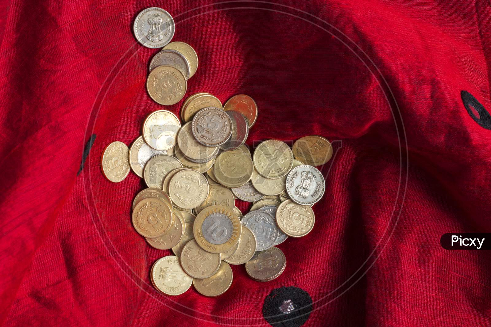 Indian five and ten rupee coins are kept in a red cloth