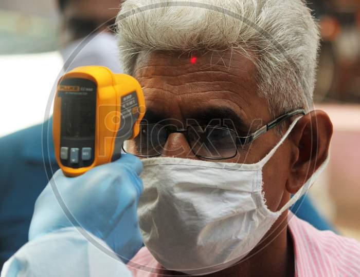 A health care worker checks the temperature of a resident at Dharavi, one of Asia's largest slums, as a preventative measure against the spread of coronavirus disease, in Mumbai, India on June 21, 2020.