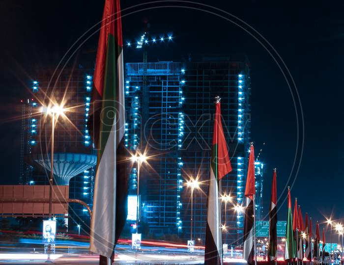 A Long Exposure Photo Of UAE Flags Alongside A Road And Garden In Downtown Dubai, United Arab Emirates.