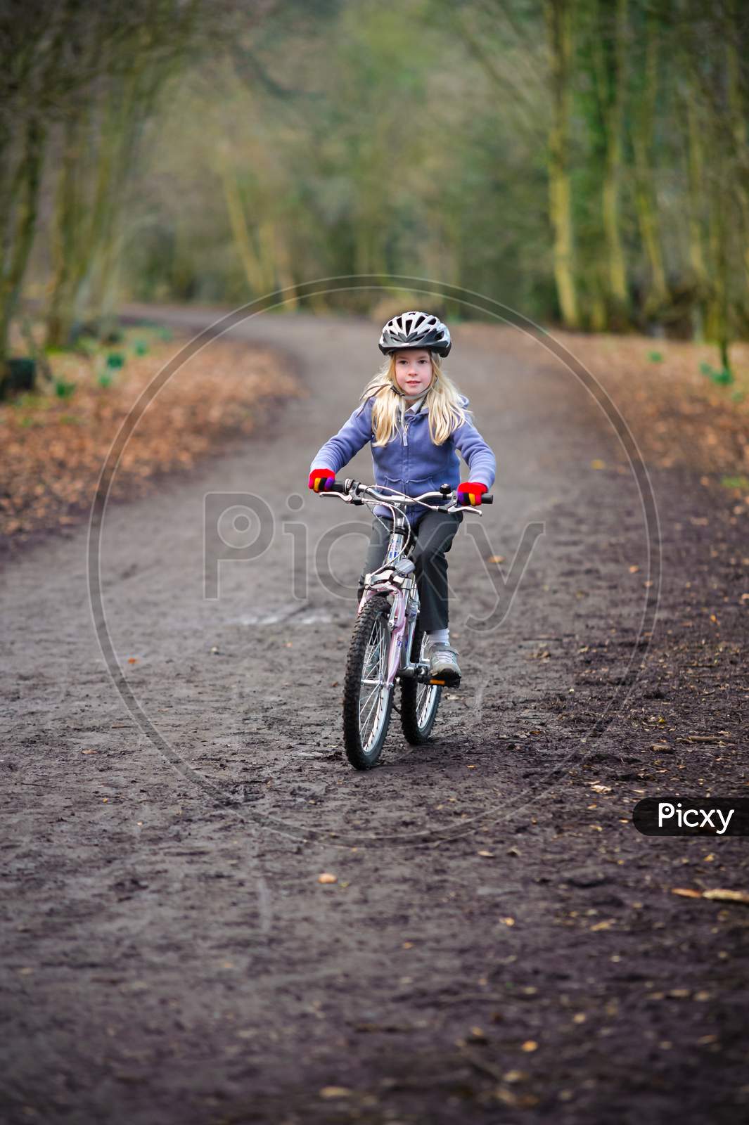 A Young Girl Rides A Bike Along A Country Track Towards The Camera