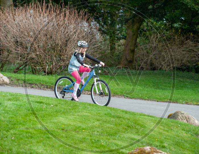 A Young Girl Rides A Bike Along A Country Road Wearing A Cycle Helmet