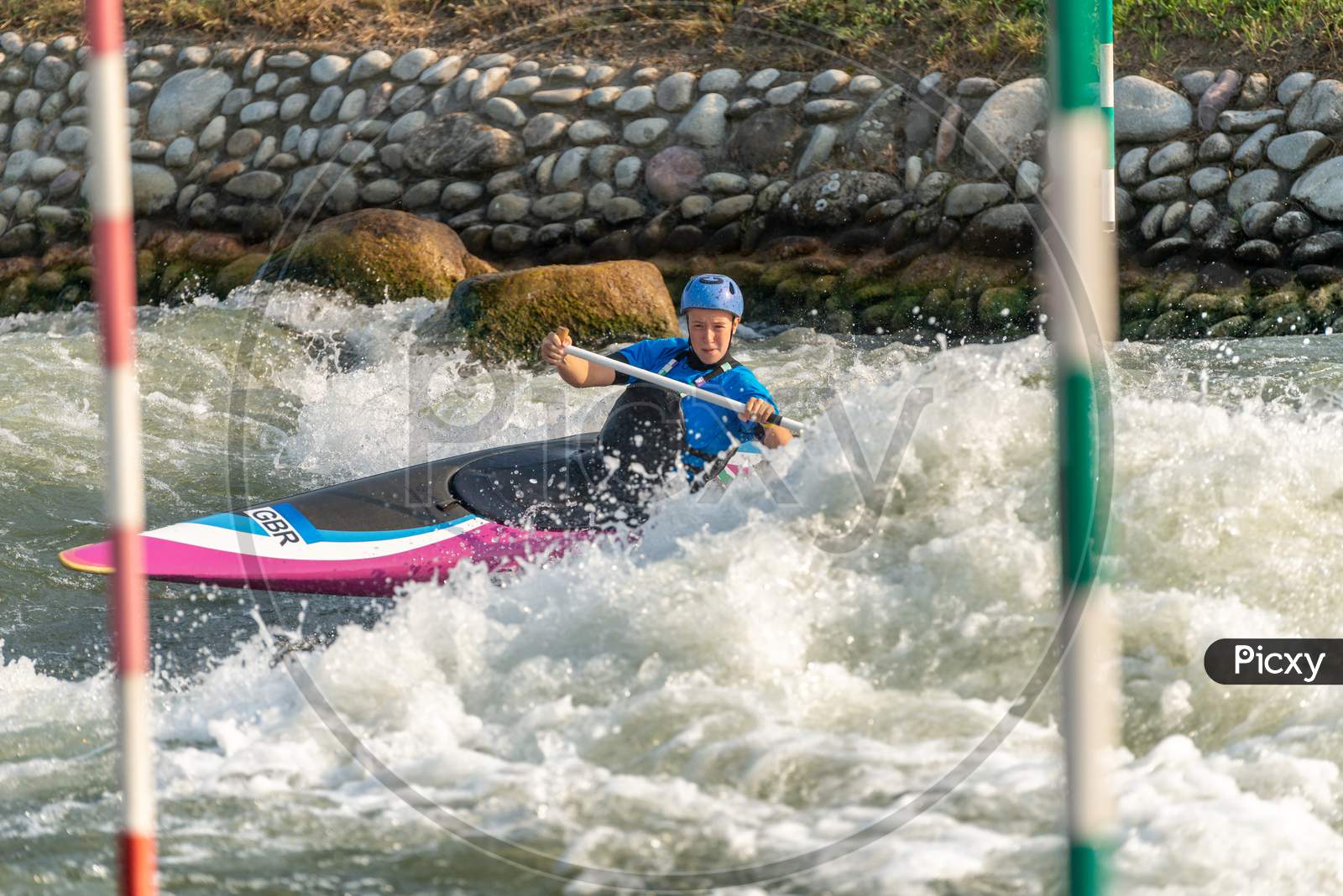 Great Britain Canoe Slalom Athlete Training On White Water With Poles In The Foreground