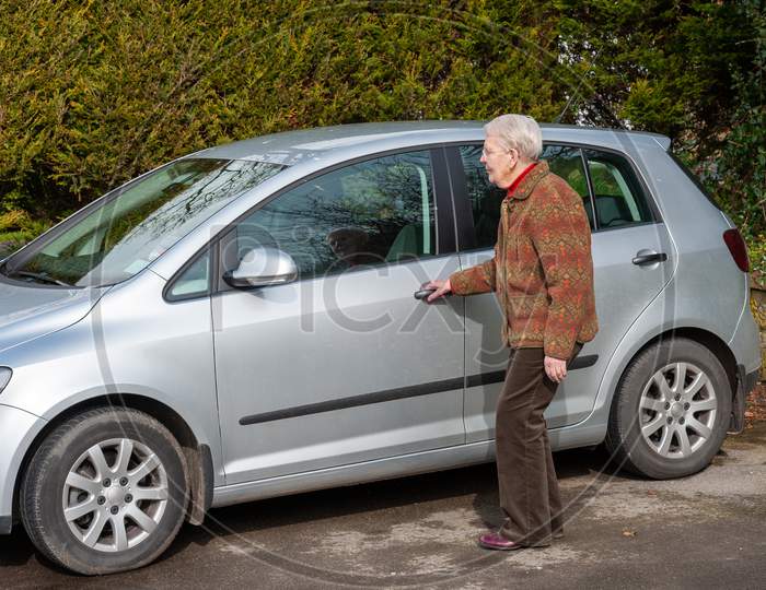 An Elderly Lady About To Open A Car Door
