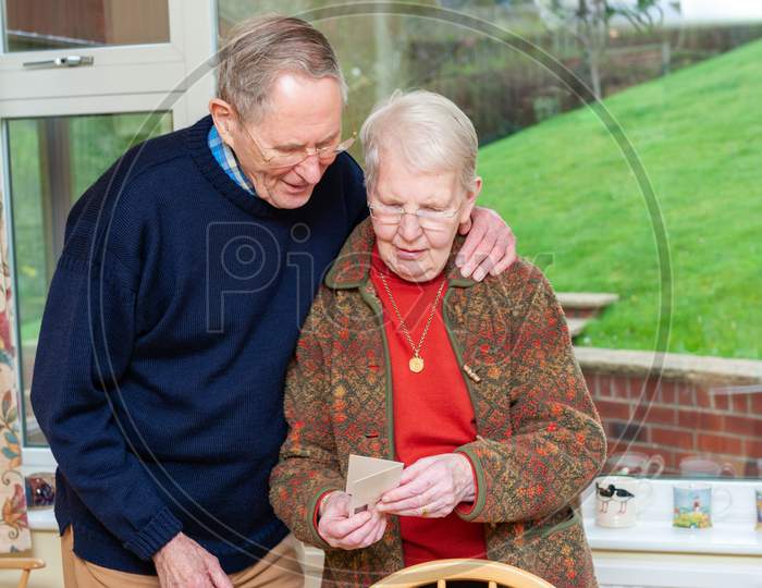 An Elderly Couple Reading A Gift Card
