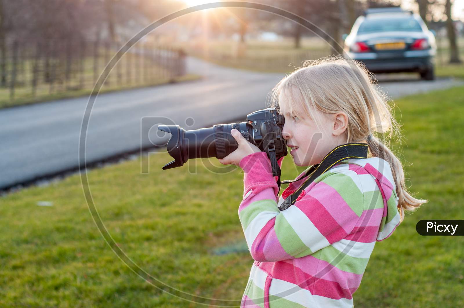A Young Blonde Girl Using A Camera With A Large Zoom Lens