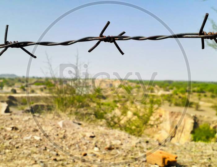 Closeup Of Thorny Iron Wire For Security On Plateau Land View From A Mountain Or Hill