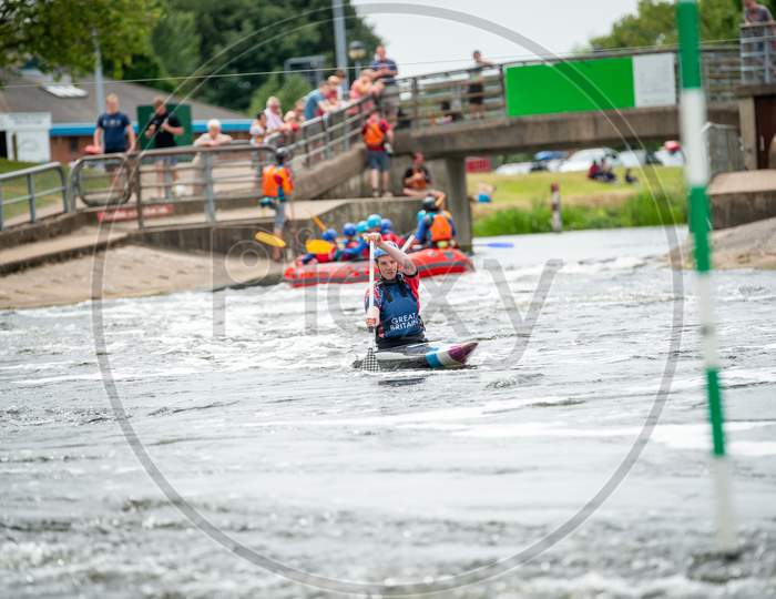 Gb Canoe Slalom Athlete Paddling Towards Camera With A Raft And Spectators In The Background. Women'S C1W Class