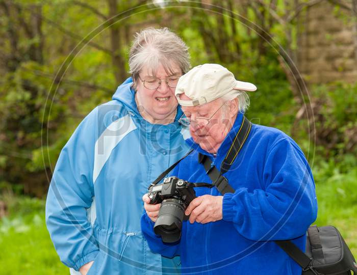 An Elderly Couple Review Photographs On The Back Of A Dslr Camera