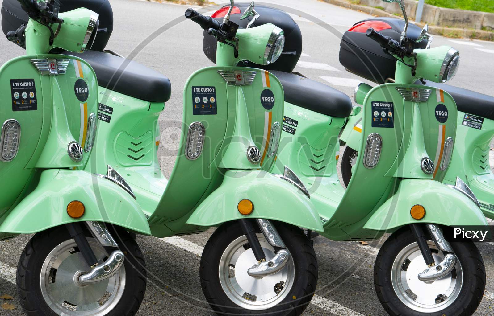 Yego electric rideshare zero emissions scooters wait for riders on the street.
