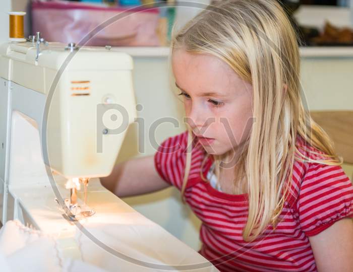 A Young Blonde Girl Using A Sewing Machine