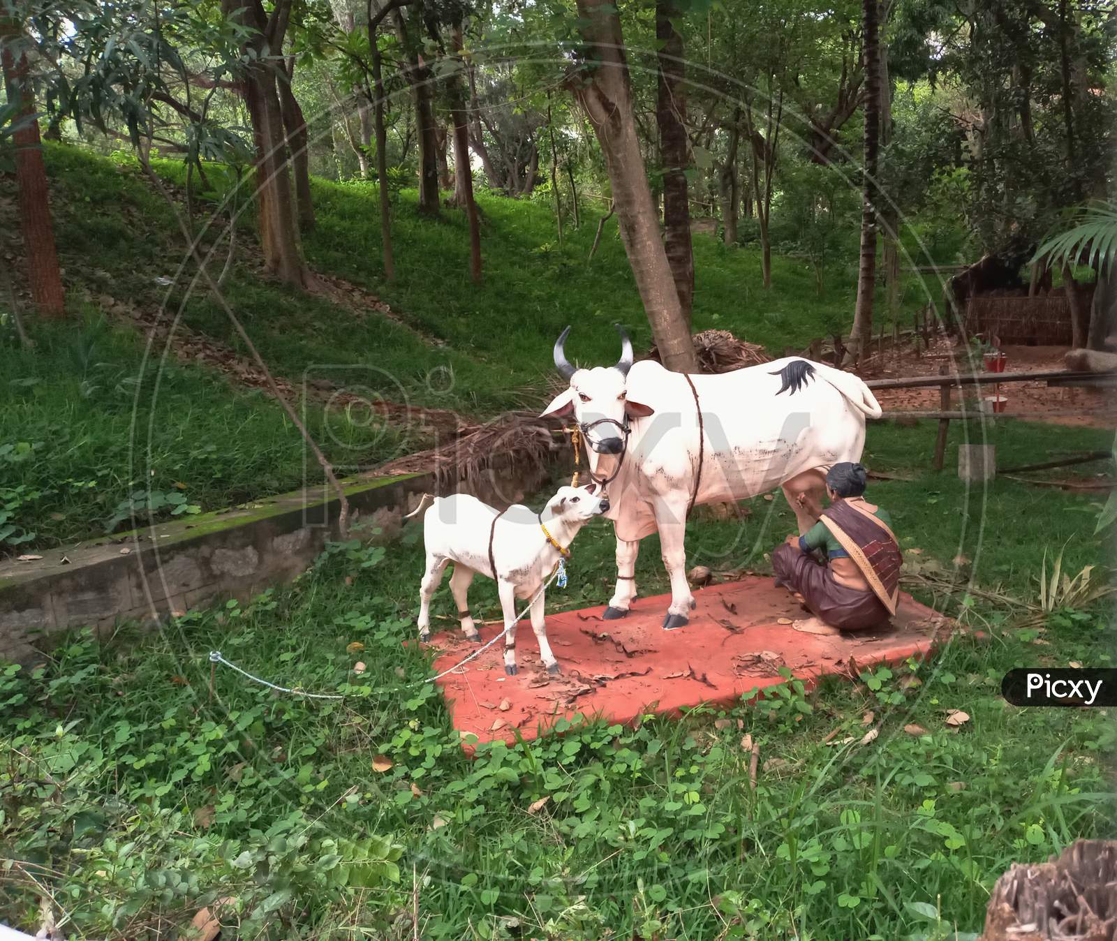 Outdoor sculptures of farm animals of cow calf and people in a folk art museum Janapada loka