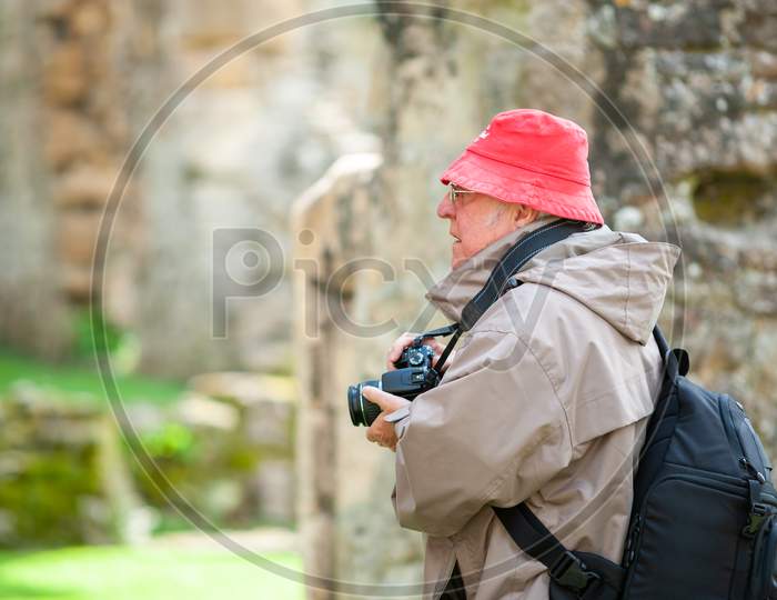 An Elderly Man With A Camera In Ancient Ruins