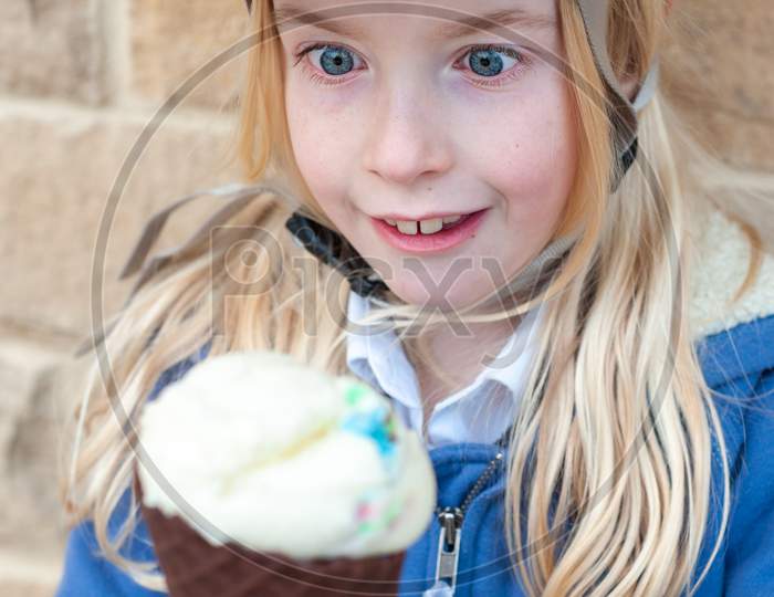 An Excited Young Blonde Girl Holds A Large Ice Cream Cone