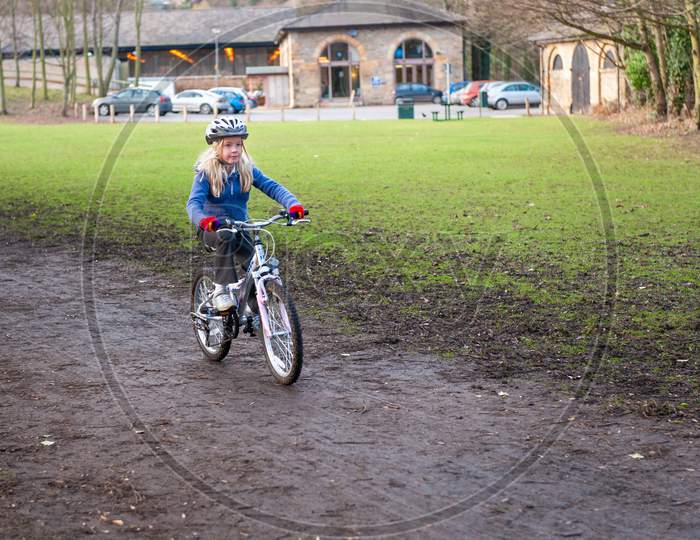 A Young Girl Rides A Bike Along A Country Track