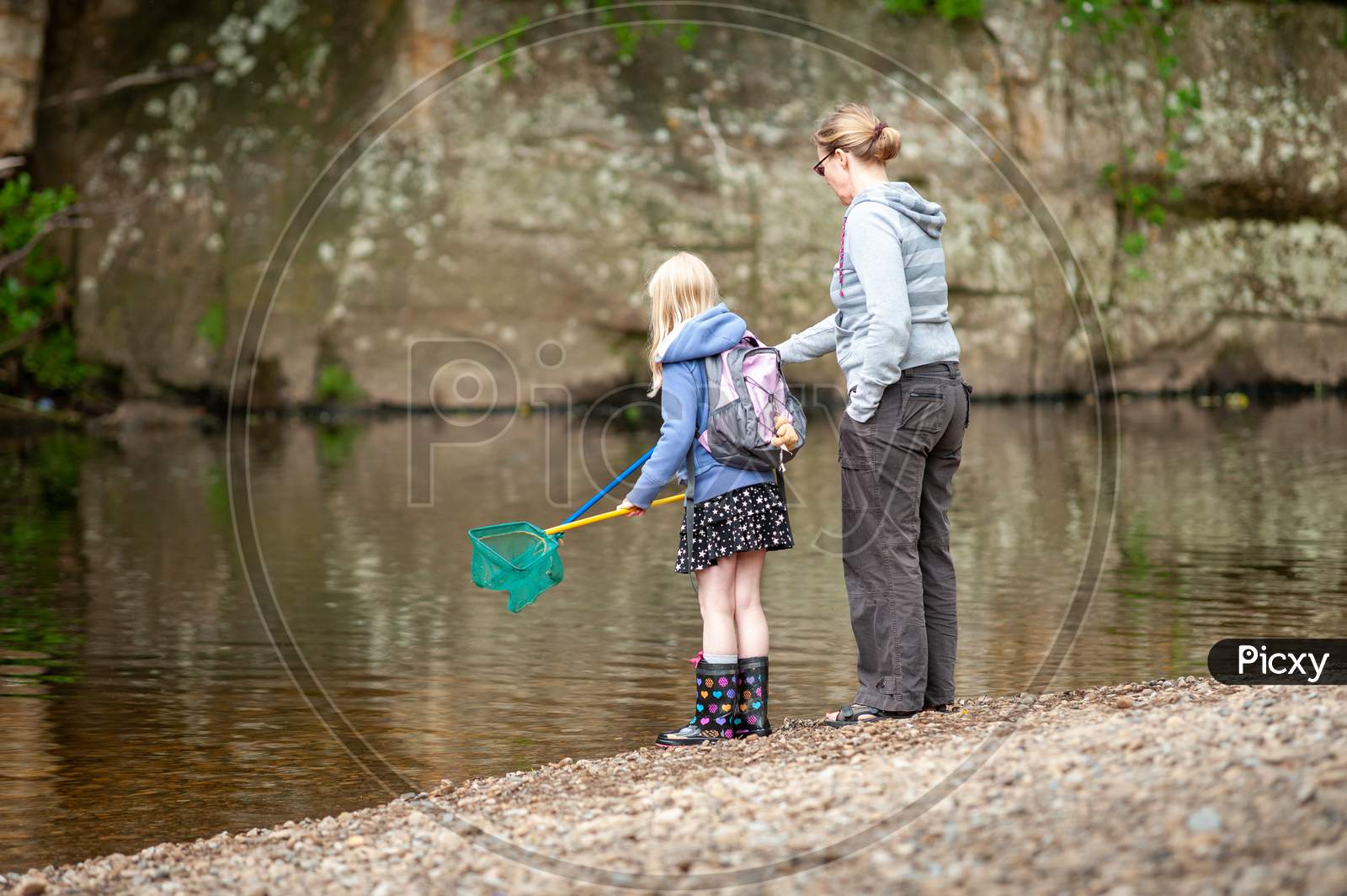 A Mother And Daughter With Fishing Nets At The Edge Of A River