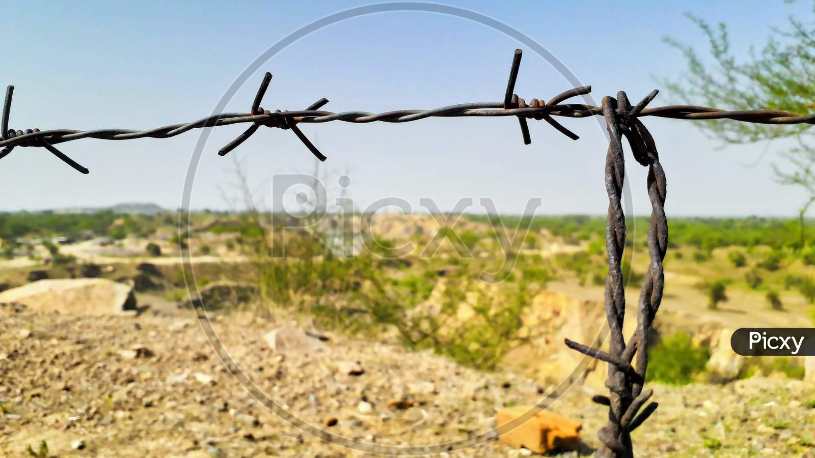 Closeup Of Thorny Iron Wire For Security On Plateau Land View From A Mountain Or Hill