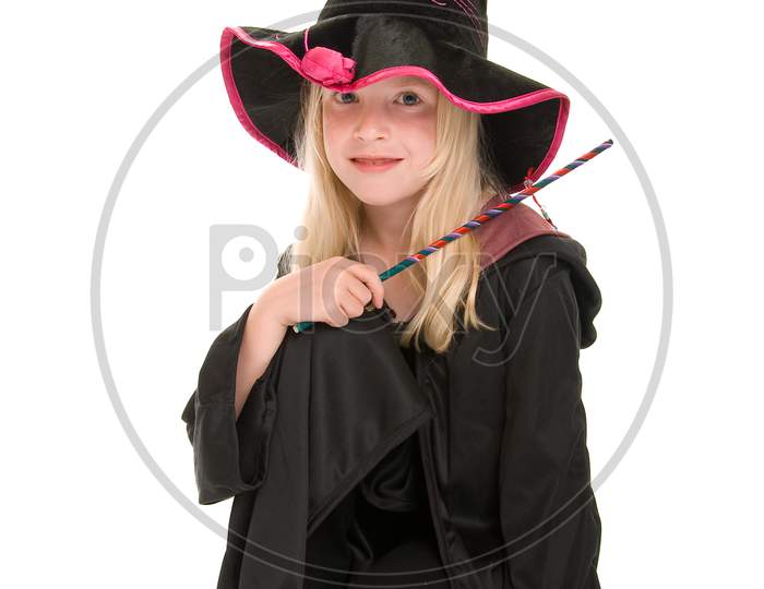 Happy Young Blonde Girl Dressed In A Witches Hat And Cloak, Holding A Wand