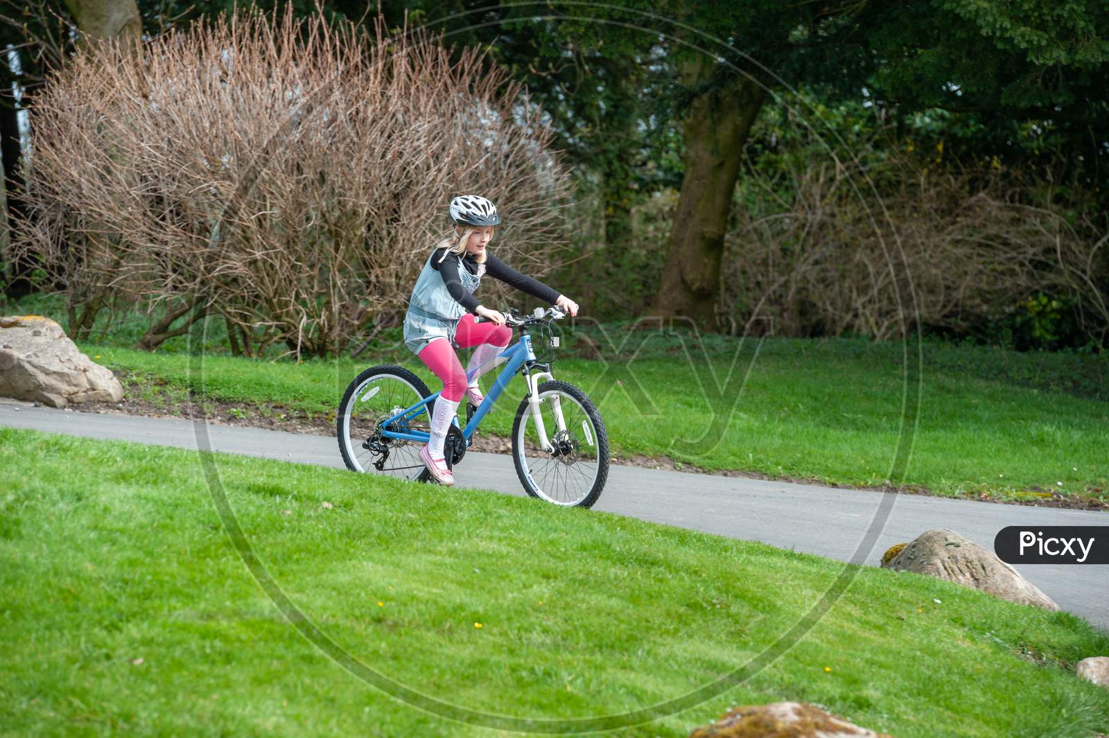 A Young Girl Rides A Bike Along A Country Road Wearing A Cycle Helmet