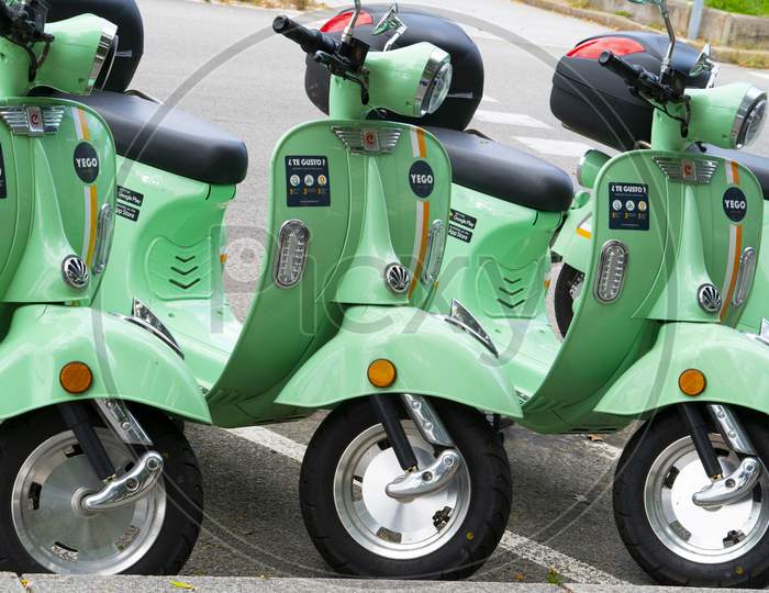 Yego electric rideshare zero emissions scooters wait for riders on the street.