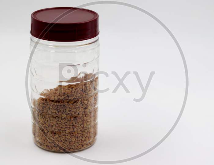 Methi Seeds in the bottle with white background