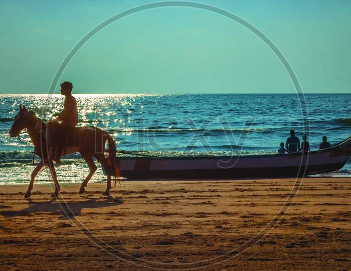 Beach Lifestyle. Early Morning Sunrise Time Horse Riding And Boat Riding On Beach Seascape.