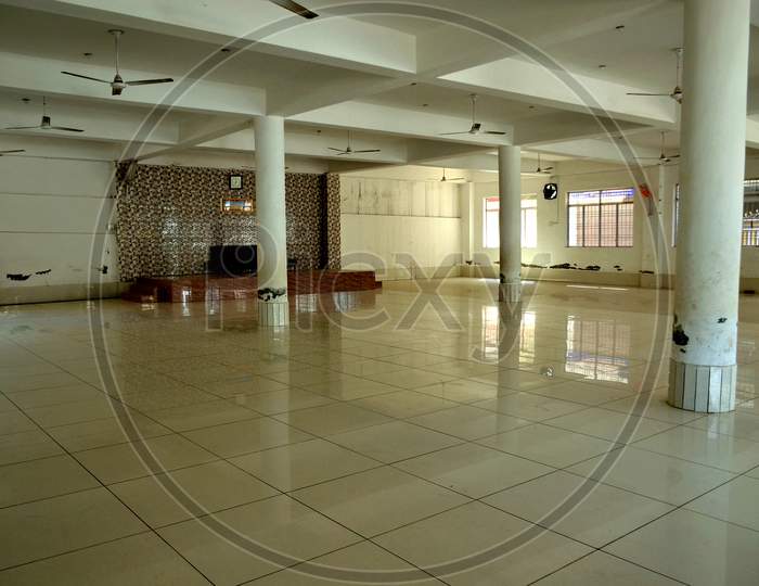 A Long Hall With Pillars And Ceiling Fans