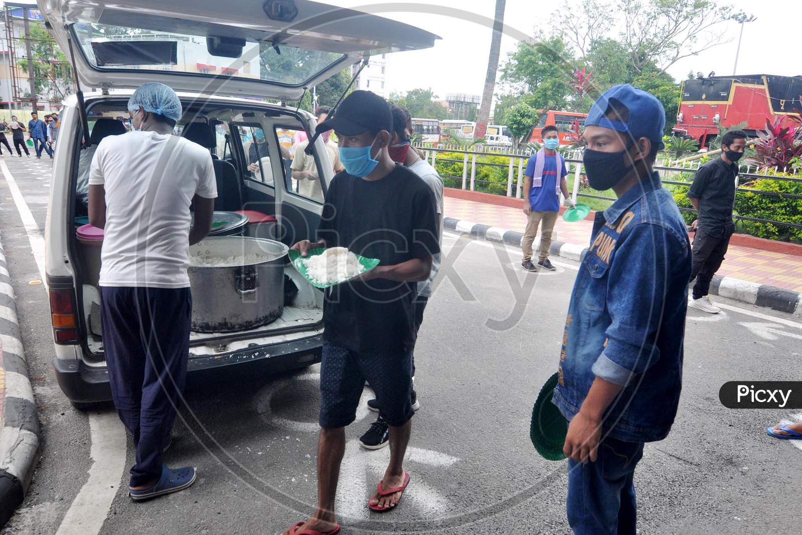 Migrants Wait In Queues To Receive cooked meals Being Distributed By The Kamrup Administration Outside The Guwahati Railway Station During Ongoing Covid-19 Lockdown, In Guwahati, Wednesday, June 3, 2020