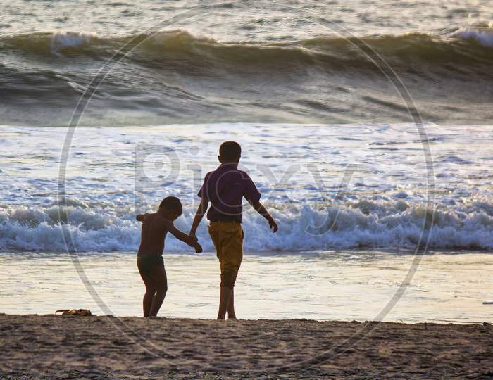 Two Kids Taking A Walk On A Beach In The City Of Goa In India